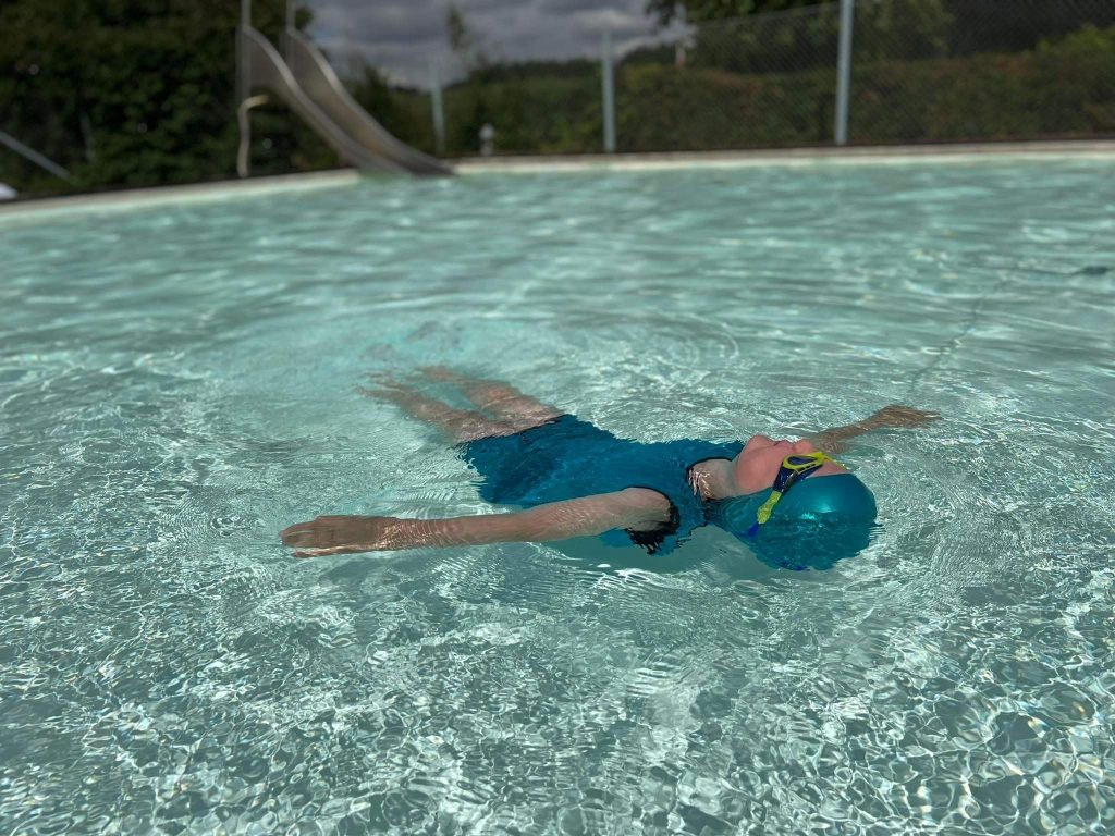 Kind liegt ruhend auf dem Rücken im Wasser