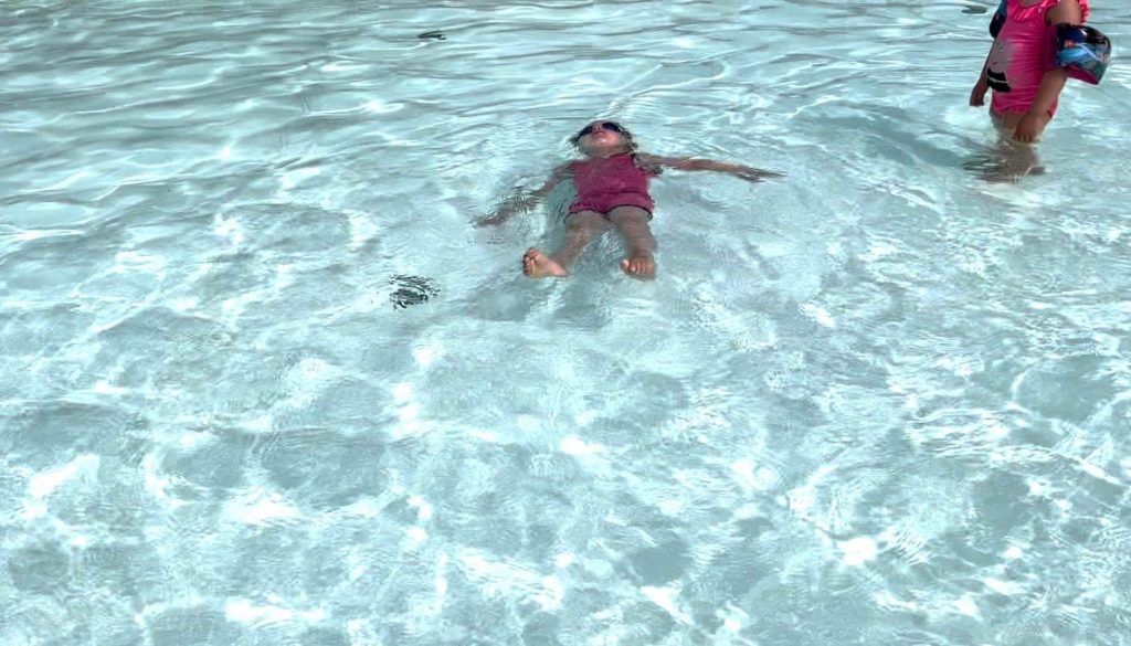 Kind liegt ruhend auf dem Rücken im Wasser